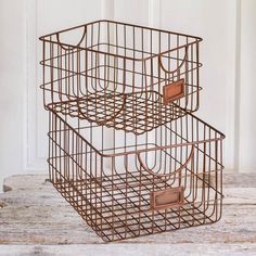 two brown wire baskets sitting on top of a wooden table next to a white door