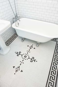 a white bath tub sitting next to a sink in a bathroom with black and white tile