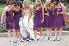 a group of women in purple dresses standing next to each other and touching their hands