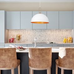 a kitchen with blue cabinets and marble counter tops, along with two bar stools