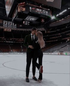 a man and woman standing next to each other in front of an ice hockey rink