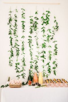 a table topped with lots of food next to a wall covered in green leaves and plants