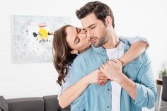 a man and woman kissing each other in the living room