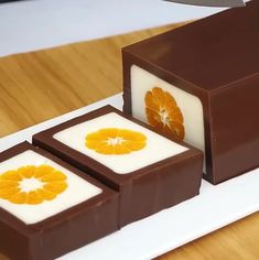 three pieces of chocolate sitting on top of a white plate next to an orange slice