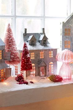 a window sill filled with snow covered houses and christmas trees on top of it