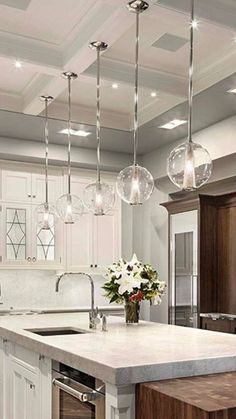 a large kitchen with an island and several lights hanging from it's ceiling over the sink