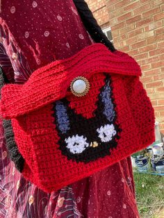 a crocheted red purse with a black and white cat face on the front