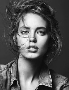 a black and white photo of a woman with her hair blowing in the wind, wearing a denim shirt