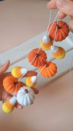 a person holding several crocheted pumpkins on a string