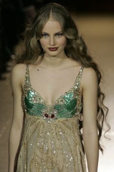 a woman walking down a runway wearing a dress with sequins and beads on it