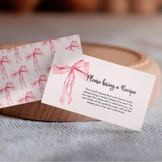 a close up of two business cards on a wooden plate with a ribbon tied around it