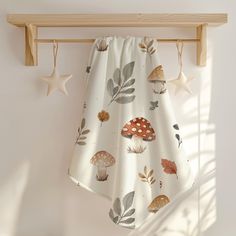 a curtain hanging on a wooden rail in front of a white wall with mushrooms and leaves