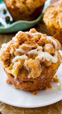 a muffin with white icing sitting on a plate next to another muffin