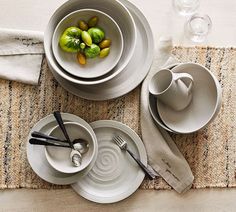 the table is set with white dishes and silver utensils, which are on top of a woven placemat