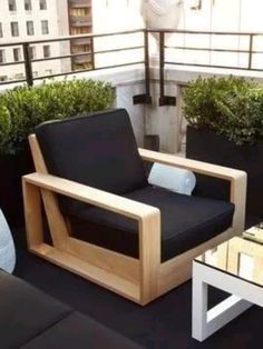 a wooden chair sitting on top of a balcony next to a planter filled with potted plants