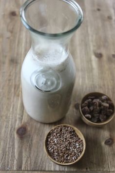 a pitcher and two small bowls filled with seeds on a wooden table top next to each other