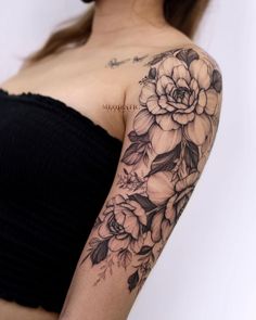 a woman with a flower tattoo on her arm and shoulder is posing for the camera