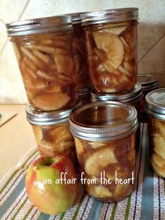 several jars filled with apple slices on top of a kitchen counter next to an apple