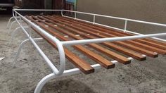 a wooden bench sitting on top of a cement ground next to a building with metal bars