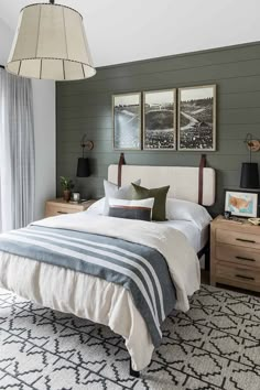 a bedroom with green walls and white bedding, two pictures on the wall above the bed