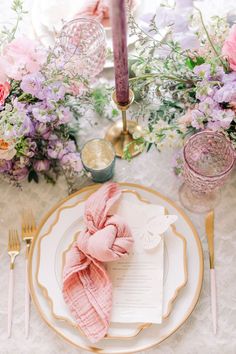 an elegant table setting with pink and purple flowers