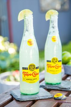 two bottles of lemonade sitting on top of a wooden table next to each other