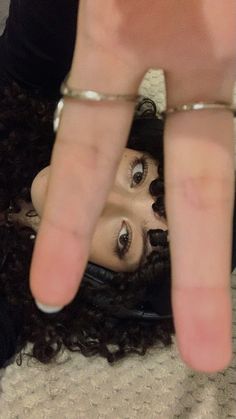 a close up of a person making a hand gesture with their fingers on her head