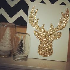 a gold glitter deer head on a white card next to two clear glass vases