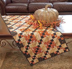 a quilted table runner on a coffee table with a pumpkin sitting on top of it