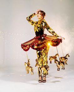 a woman is dressed in gold and black with horses on the string, while holding her hands behind her head