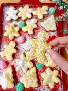 a person holding up a cookie shaped like a gingerbread on top of a red tray