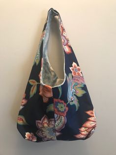 a floral bag hanging on the wall with its handles folded up to show it's inner compartment