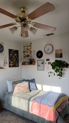 a bedroom with a bed, ceiling fan and various pictures on the wall above it