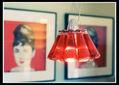 two red vases hanging from a ceiling with pictures on the wall in the background