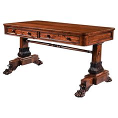 A George IV Period Rosewood Library Table With Carved Lions Paw Feet English Circa 1820- 1830 This handsome table would have been commissioned for a grand library or study. The overhanging top has rounded corners and the frieze below echoes this detail. Likewise the turned stretcher which joins the two end supports is another feature with pronounced curves. By contrast the end supports themselves are made up largely of squared corners and straight lines but they are enlivened considerably by beautifully carved winged lions paw feet and, most noticeably, lotus flower carving to the base of each support. In the frieze of the piece are two drawers with their original patinated turned wooden handles having faux drawers to the opposing side enabling this library table to stand freely within the Lotus Flower Carving, Grand Library, Lions Paw, George Iv, Library Table, Lion Paw, Drum Table, Birdseye Maple, Flower Carving