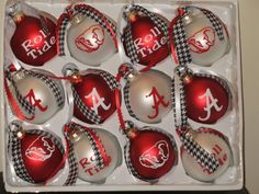 twelve red and white christmas ornaments with monogrammed letters in a box on a table