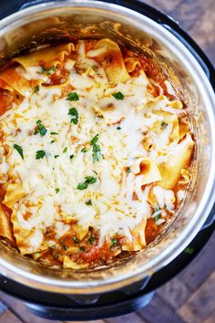 an overhead view of a crock pot filled with pasta and sauce, garnished with parmesan cheese