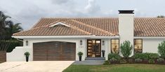 a white house with brown tile roof and two garages