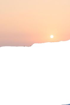 a man riding skis down the side of a snow covered slope under a sunset