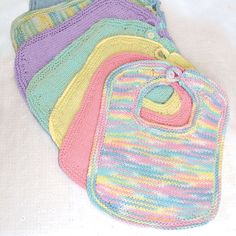 four crocheted baby bibs laying on top of each other