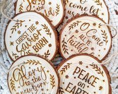 four wooden ornaments with words on them sitting on a white cloth covered tablecloth in the shape of christmas tree slices