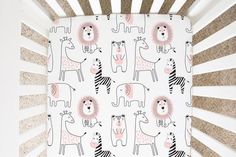 a white crib with pink and black zebras on it next to a wall