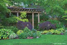 an outdoor garden with lots of plants and flowers in the center, including purple bushes