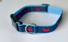 a blue dog collar with red whale on it's side and a black metal ring