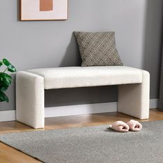 a white bench sitting on top of a wooden floor next to a potted plant