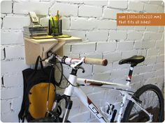 a bicycle is parked next to a white brick wall with writing on it and a school bag