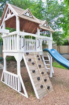 a wooden play structure with a slide and climbing frame