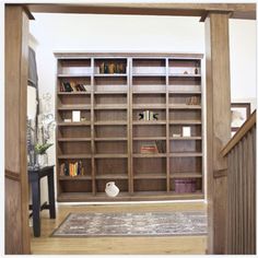 an open bookcase with many books on it in a living room next to stairs