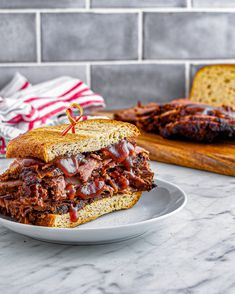 a plate with a sandwich cut in half sitting on a table next to a loaf of bread