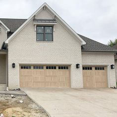 a white brick house with two garage doors